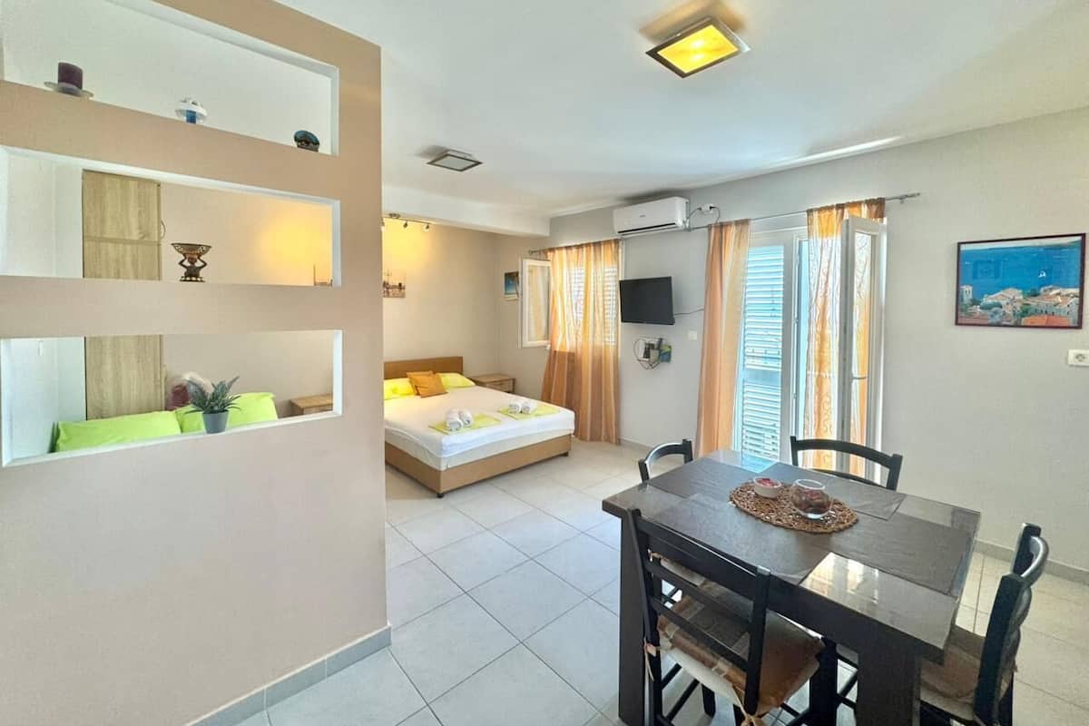 A modern hotel room with a bed, a dining table, and a TV.