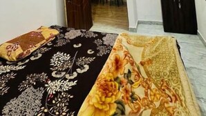 Une chambre à coucher comprenant un lit, un ventilateur de plafond, une armoire et une porte donnant sur une autre pièce.