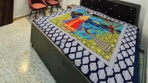 Een slaapkamer met een bed, twee stoelen, een kledingkast en een wandplank.