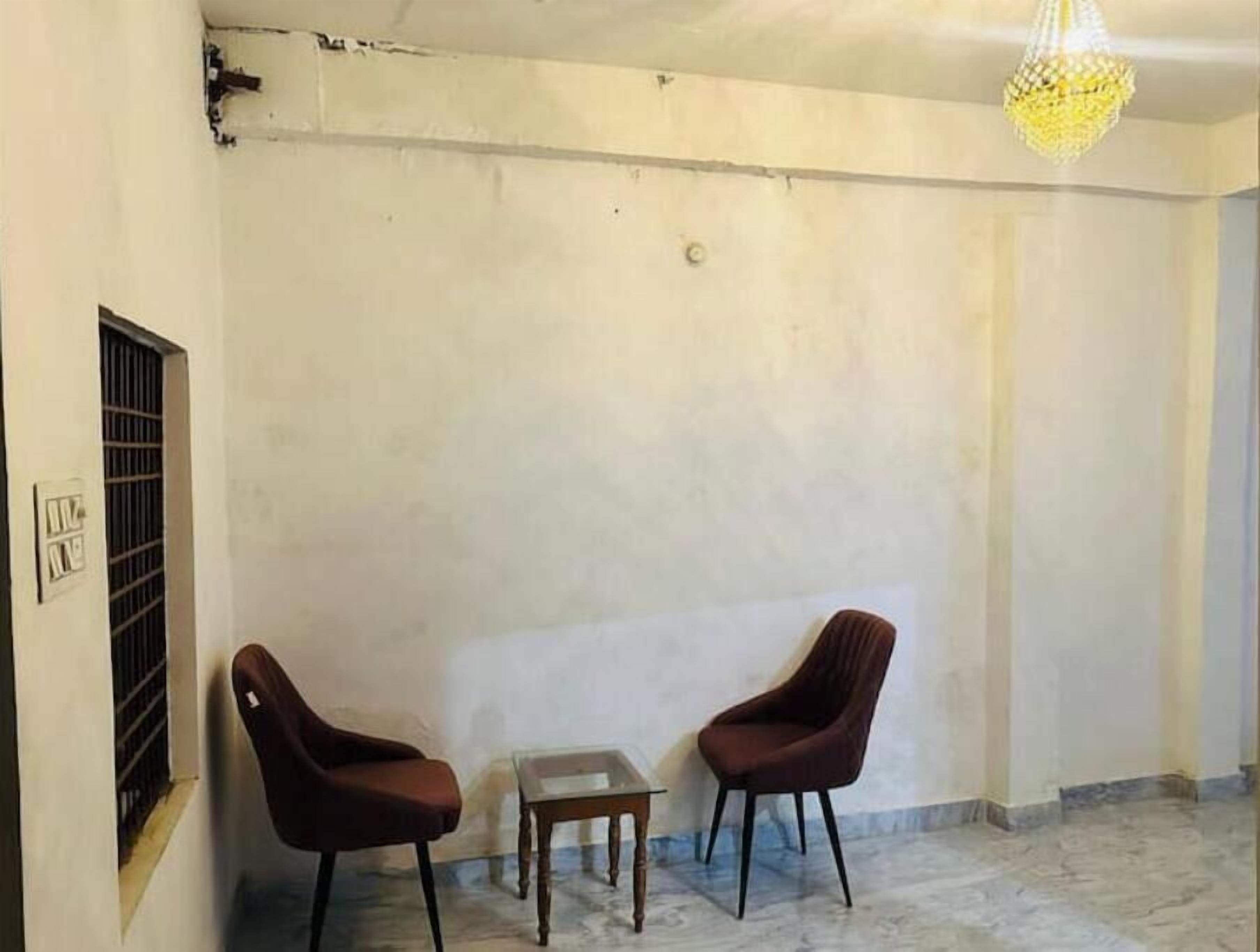 Een kamer met twee bruine stoelen, een tafeltje en een hanglamp.