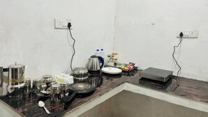 Een keuken met een marmeren aanrecht, diverse keukengerei, een waterkoker, een bord en een klein apparaat.