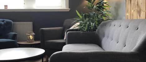 A modern living room with a grey sofa, a round coffee table, and a potted plant.