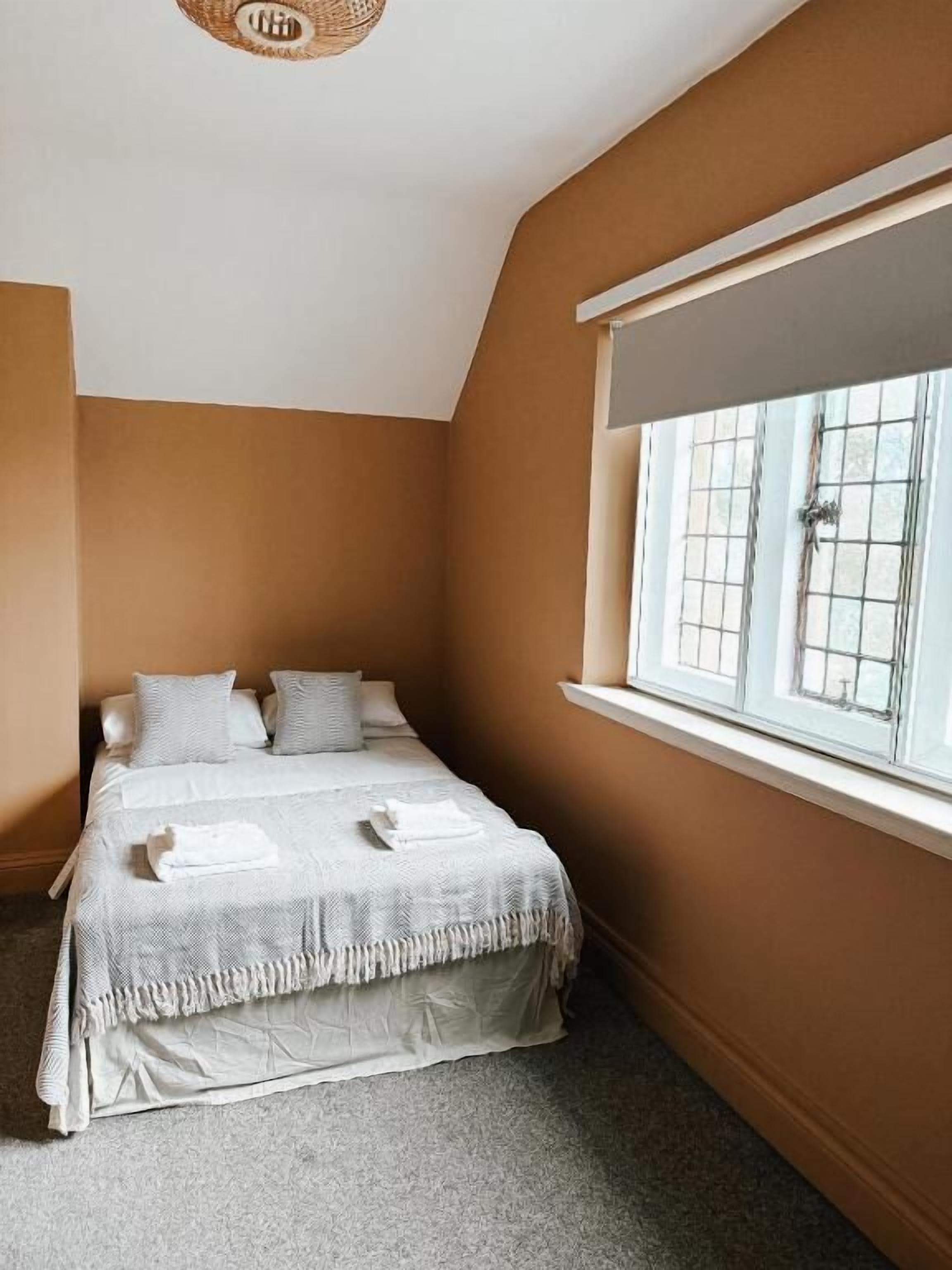Una camera da letto con un letto, una finestra con tende e una lampada a soffitto.