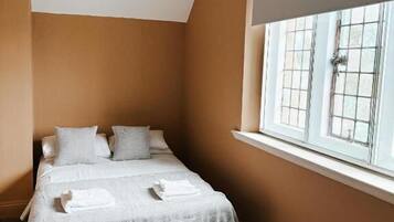 Una camera da letto con un letto, una finestra con tende e una lampada a soffitto.