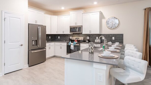 A modern kitchen with white cabinets, stainless steel appliances, and a central island with seating.