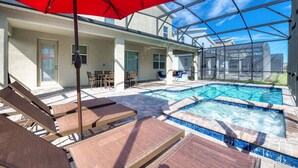 A pool area with lounge chairs and a red umbrella.
