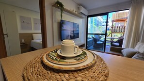 Una habitación con cama, televisión y ventana con vistas a mobiliario exterior.