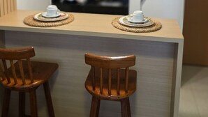 A kitchen with two hanging pendant lights, a central island with two stools, and a refrigerator in the background. - Flat vip 02B Bela Vista by La Playa (Ipojuca)