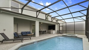 A swimming pool with lounge chairs and a covered patio area.