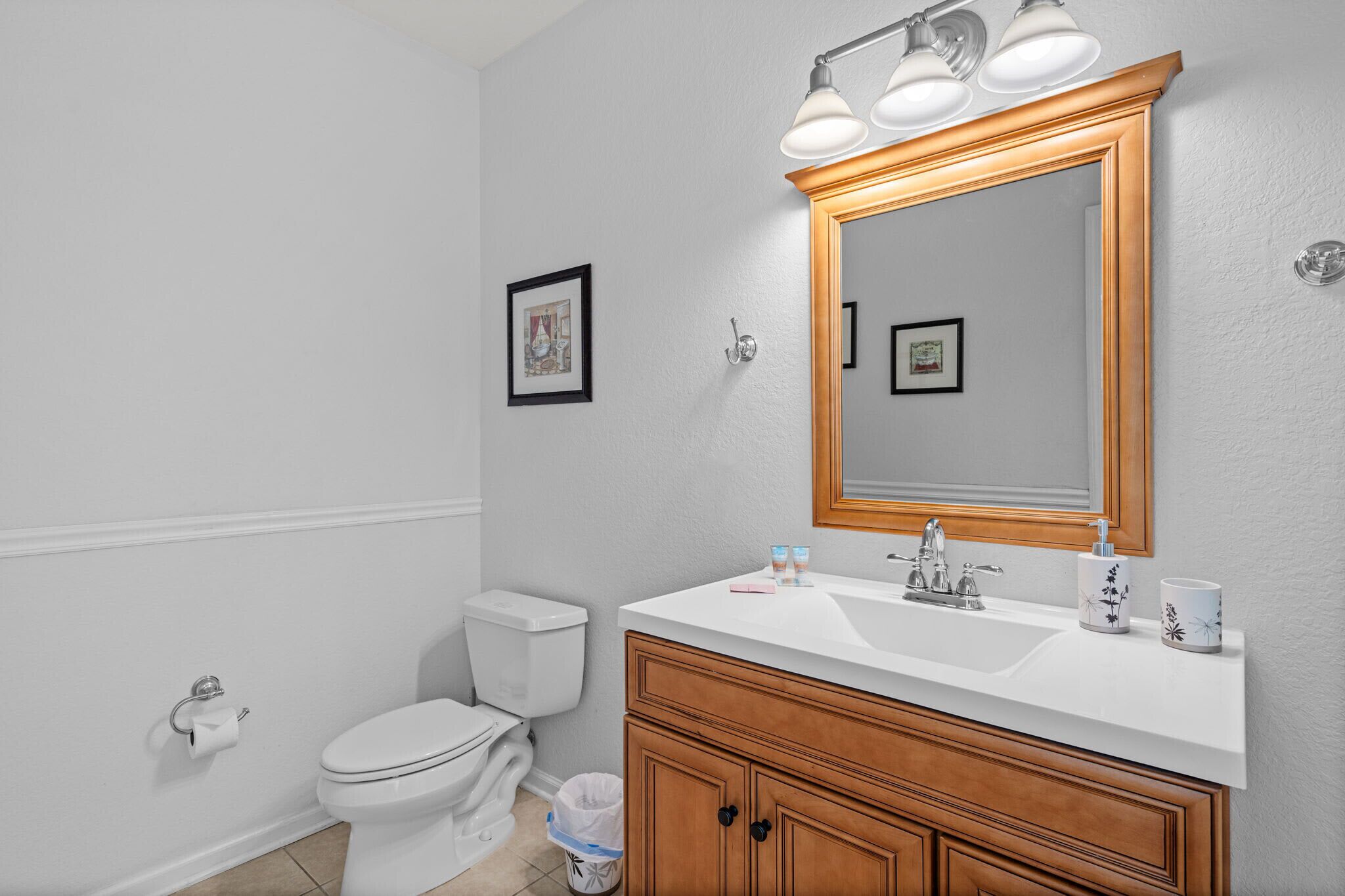 A bathroom with a white sink, wooden vanity, and a large mirror with lights.