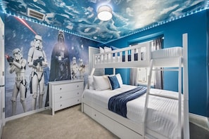Une chambre avec un lit superposé, une fresque murale sur le thème de Star Wars et un mur d’accent bleu.