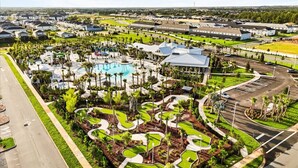 An aerial view of a resort with a swimming pool, landscaped areas, and a parking lot.