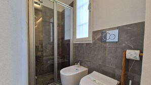 Une salle de bain moderne avec une douche à parois de verre, un bidet et des toilettes.