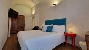 Une chambre à coucher avec un lit, une table de chevet rouge, des toilettes blanches et une armoire en bois.