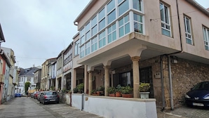 A street view of a row of buildings with a covered walkway and parked cars. - Real 43 *Good road (Neda)