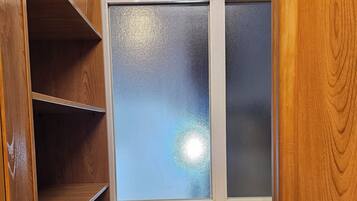 Un armadio in legno con una finestra in vetro satinato, ripiani in legno e una porta bianca.