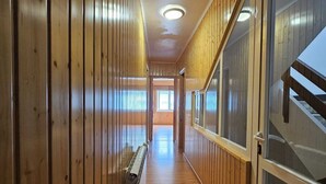 A hallway with wooden paneling, a radiator, and a glass door leading to a staircase. - Real 43 *Good road (Neda)