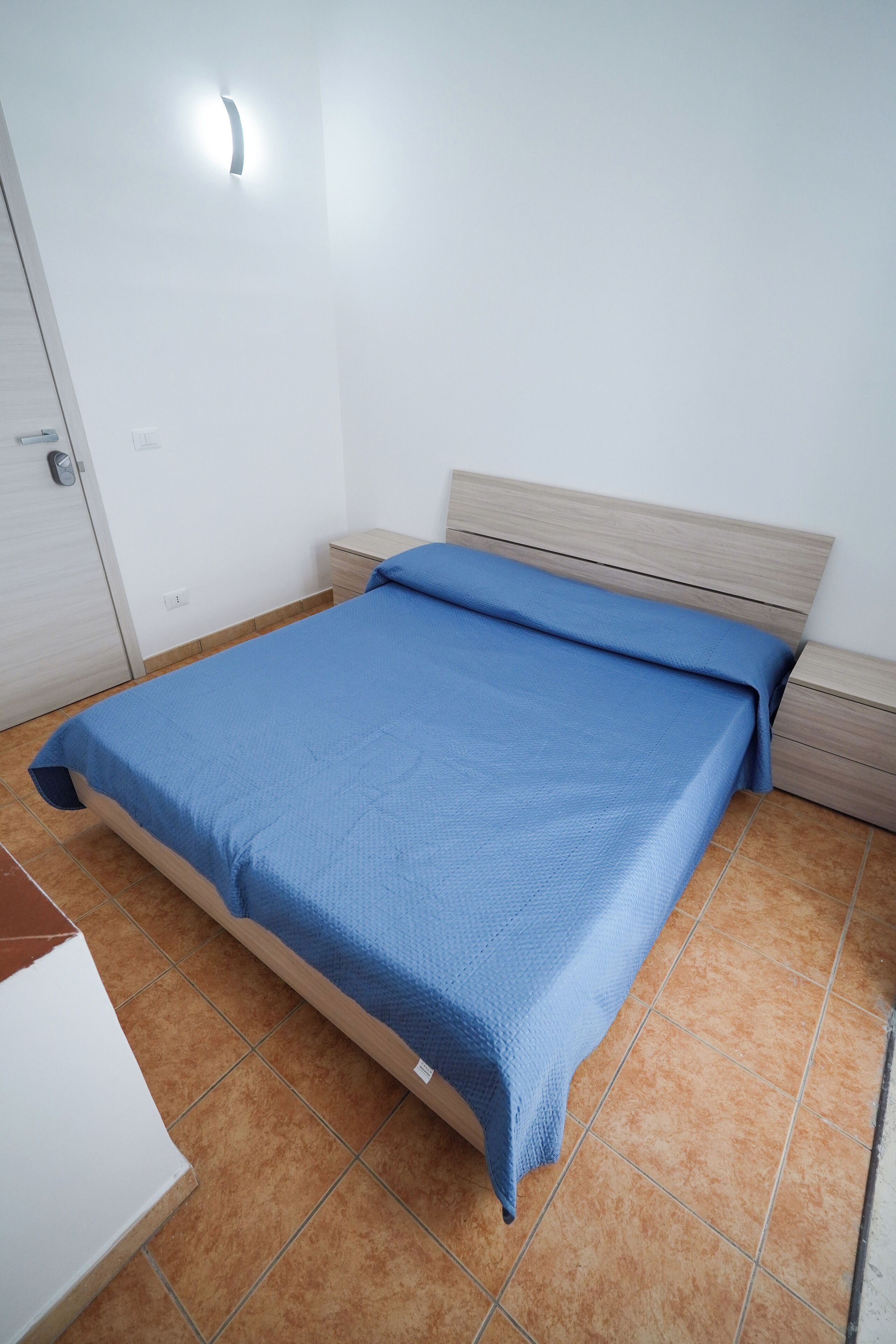 Une chambre à coucher comprenant un lit, une table de chevet, une armoire et un luminaire fixé au mur.