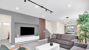 A modern living room with a flat-screen TV, grey sofa, and a coffee table.