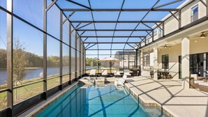 Une piscine dotée d’une structure en verre, d’un espace extérieur aménagé et offrant une vue sur un lac.