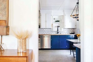 Een moderne keuken met witte kastjes, een blauw aanrecht en een roestvrijstalen vaatwasser.
