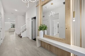 A modern hallway with a wooden bench, a large mirror, and a potted plant. - Last Minute Disney! Private Pool, Game Room & Themed Bedrooms. Book Now! #118059 (Orlando)