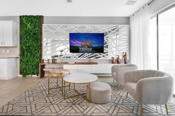 Un salón moderno con televisor de pantalla plana, un jardín vertical verde y una consola blanca.