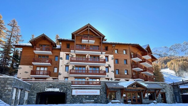 Un hôtel à plusieurs étages, doté de balcons en bois et d’une façade en pierre.