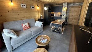 Un salon chaleureux avec un canapé gris, une table basse en bois et une table à manger avec des chaises.