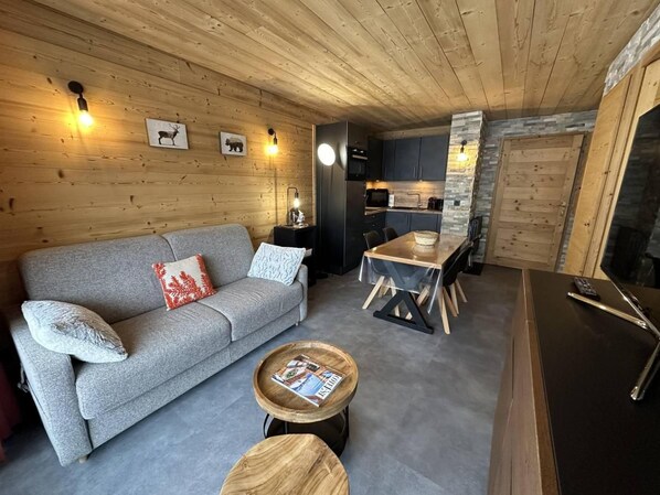 A cozy living area with a grey sofa, a wooden coffee table, and a dining table with chairs.