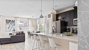 Une cuisine moderne dotée d’un grand îlot central, de tabourets de bar et d’un coin repas comprenant un canapé et des chaises.