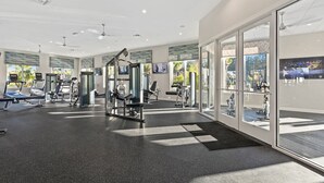 Une salle de sport moderne dotée de divers appareils d’exercice, de grandes fenêtres et d’un intérieur lumineux.