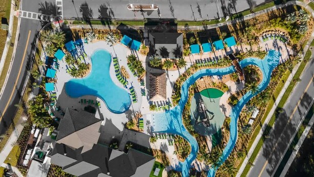 Vue aérienne d’un complexe hôtelier doté de plusieurs piscines, d’un grand bâtiment et d’une route adjacente à la propriété.