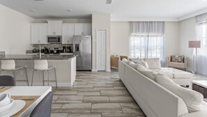 A modern kitchen with white cabinets, a central island, and stainless steel appliances.