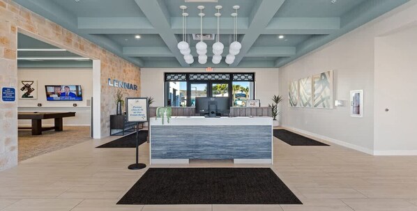A reception area with a modern design, featuring a reception desk, a television, and artwork on the walls.