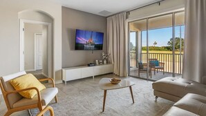 Una sala de estar moderna con una televisión de pantalla plana, un sofá, una silla y una mesita.
