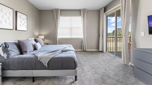 Un dormitorio con cama, ventana con cortinas, cámara en el techo y vista al exterior.
