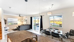A modern kitchen with granite countertops, stainless steel sinks, and a dining area with a glass table and chairs.