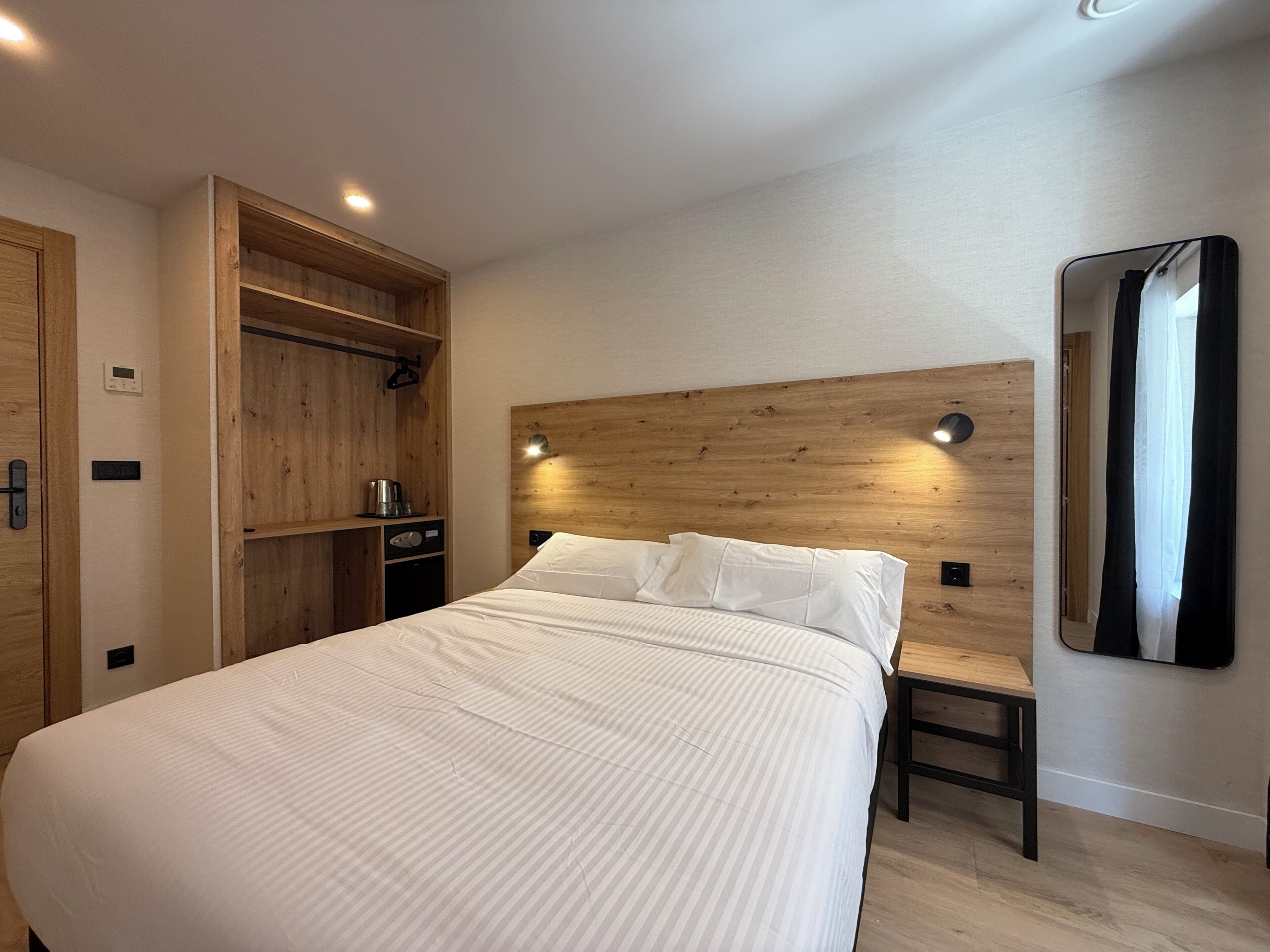 Un dormitorio moderno con una cama grande, cabecera de madera, mesita de noche y armario empotrado.