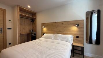 Quarto moderno com cama grande, cabeceira de madeira, mesa de cabeceira e guarda-roupa embutido.