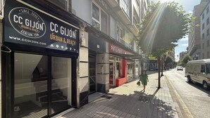 A storefront with a large glass window and a black awning displaying the name 'CC GIJÓN URBAN & BEACH'.