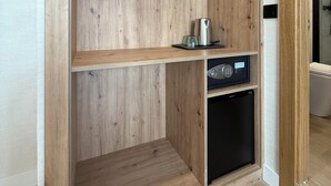 A wooden closet with a hanging rod, a shelf, and a built-in appliance.