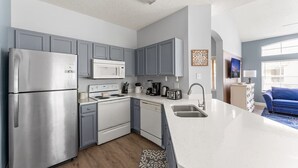 Una cocina moderna con gabinetes grises, electrodomésticos de acero inoxidable y una encimera blanca.