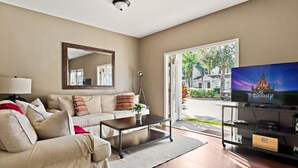 A living room with a sofa, coffee table, and a television on a stand.