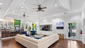 A spacious living area with a large sectional sofa, a kitchen with a built-in oven, and a dining area with a table and chairs.