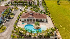 Una casa grande con piscina, rodeada de palmeras y un césped cuidado.