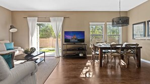 Una sala de estar con televisor, mesa de comedor y sillas.