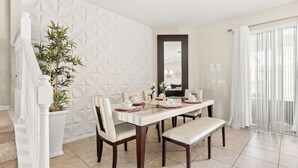 A dining area with a white table set for four, surrounded by chairs. There is a potted plant to the left and a large mirror on the wall. - Disney Getaway! Private Pool & Themed Bedrooms. Book Now! #Solt429 (Orlando)