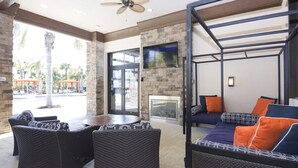 A modern outdoor seating area with wicker furniture, a round table, and a sofa with orange cushions. - Disney Getaway! Private Pool & Themed Bedrooms. Book Now! #Solt429 (Orlando)