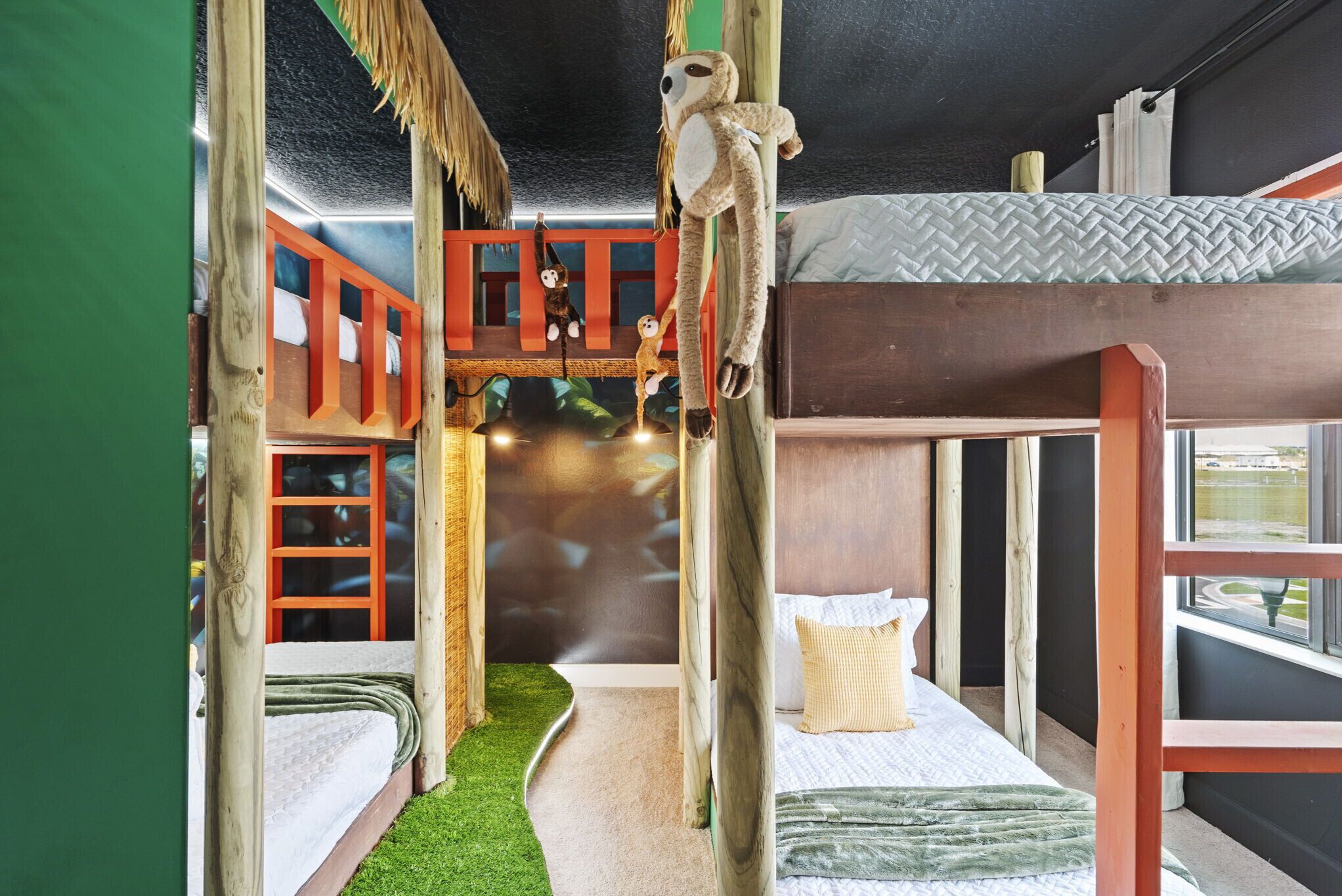 A room with bunk beds, a small play area with a slide, and a window with a view of the outside.